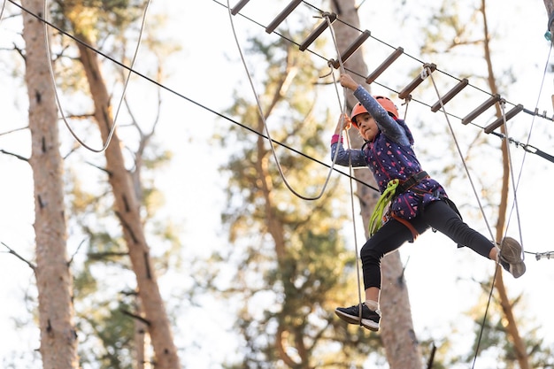 Girl climbing in adventure park is a place which can contain a wide variety of elements, such as rope climbing exercises, obstacle courses and zip-lines.