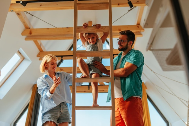 Girl climbing ladder with the help of her parents