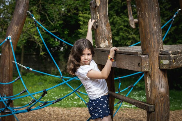 女の子が公園の木の上でロープスイングを登る