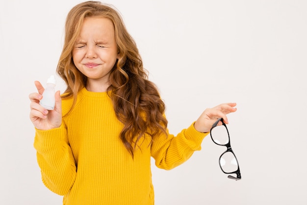 Girl closed her eyes after instillation of eyes in a solution and holds glasses