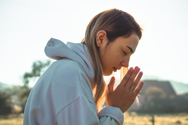 Girl closed her eyes, praying outdoors