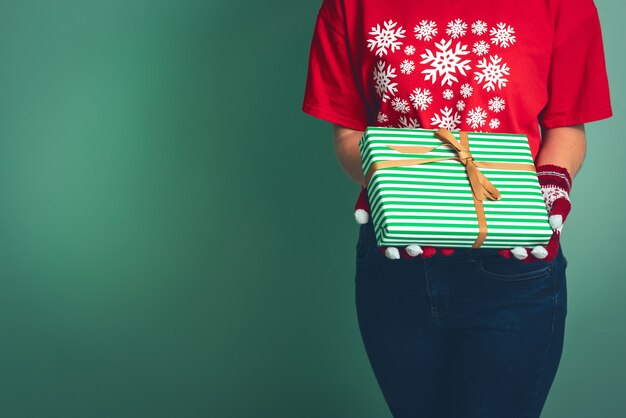 Girl in clothes with a Christmas ornament holds a gift box