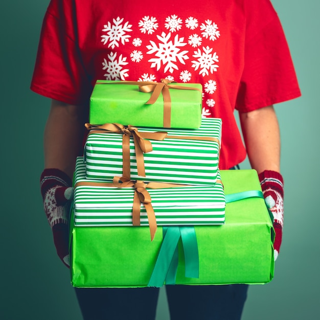 Girl in clothes with a Christmas ornament holds gift boxes