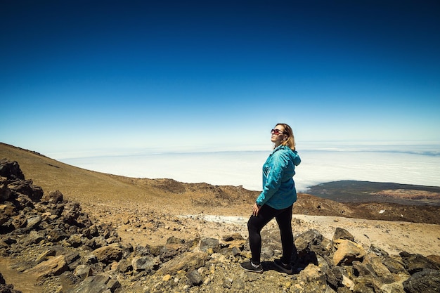 Girl over the clouds on top of the mountain by the volcano Teide Tenerife Canary Island Spain