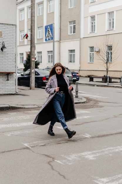 a girl in a coat crosses the road