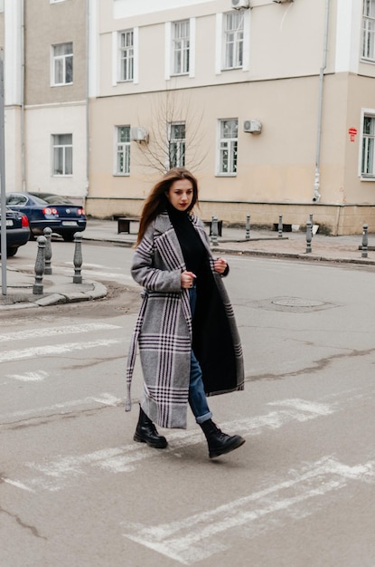 a girl in a coat crosses the road