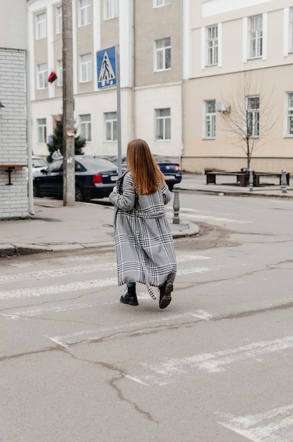 a girl in a coat crosses the road