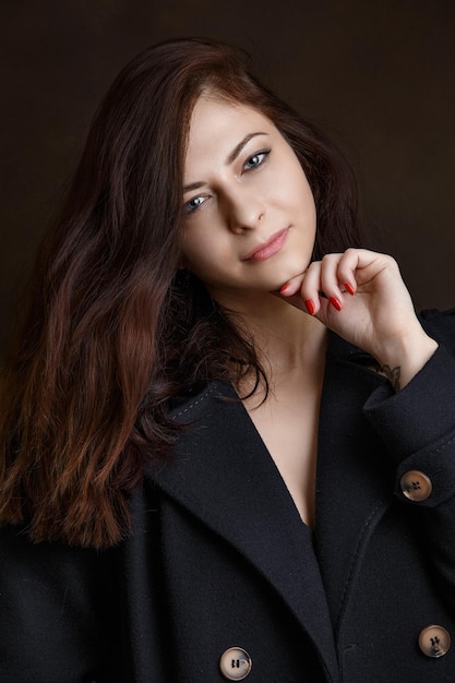 Girl in a coat on a dark background, brunette close-up