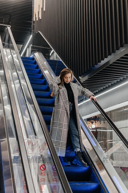 a girl in a coat goes down the escalator