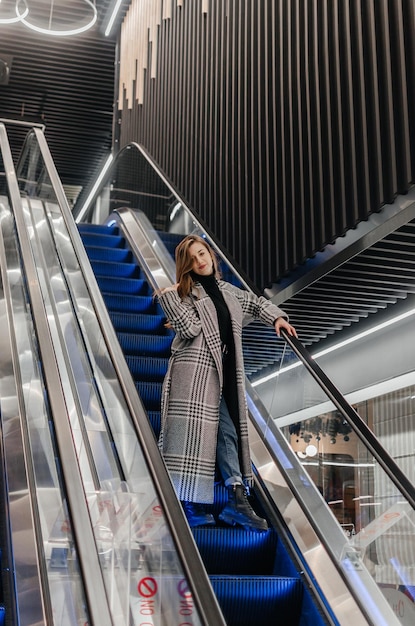a girl in a coat goes down the escalator