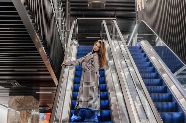 a girl in a coat goes down the escalator