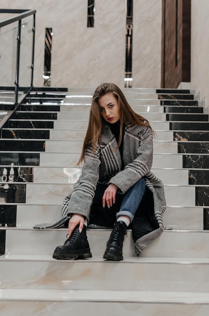 a girl in a coat sits on the stairs