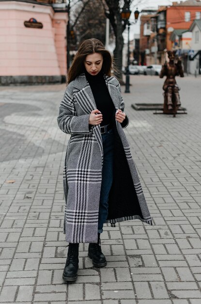 a girl in a coat walks around the city