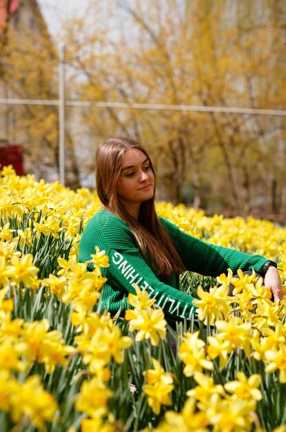 Foto una ragazza raccoglie fiori nel suo giardino con narcisi all'inizio della primavera