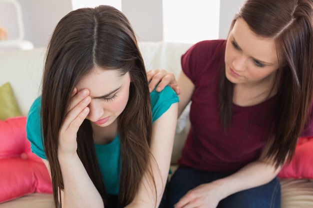 Ragazza che conforta il suo amico che piange sul divano