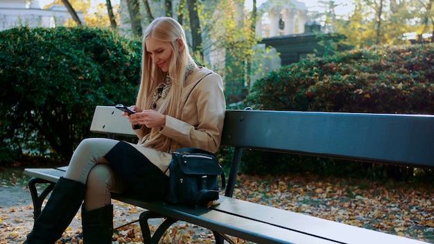 Фото Девушка общается в смартфоне в городском парке на скамейке