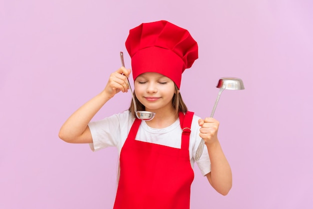 A girl in a cook's costume holds a ladle in her hands and is going to cook soup the child dreams of becoming a cook