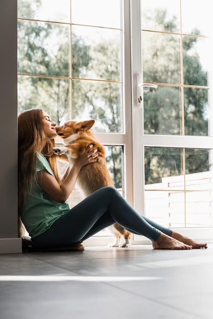 Girl and Corgi dog at home Young woman sitting and play with Welsh Corgi Pembroke Lifestyle with domestic pet