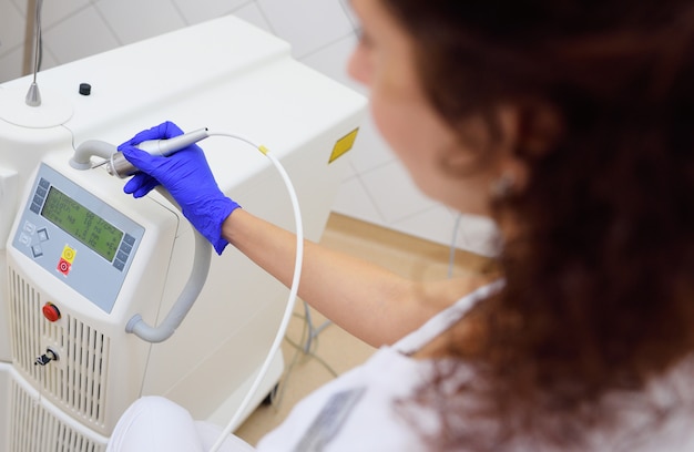 Girl cosmetologist on the surface of a laser apparatus or installation for aesthetic medicine.