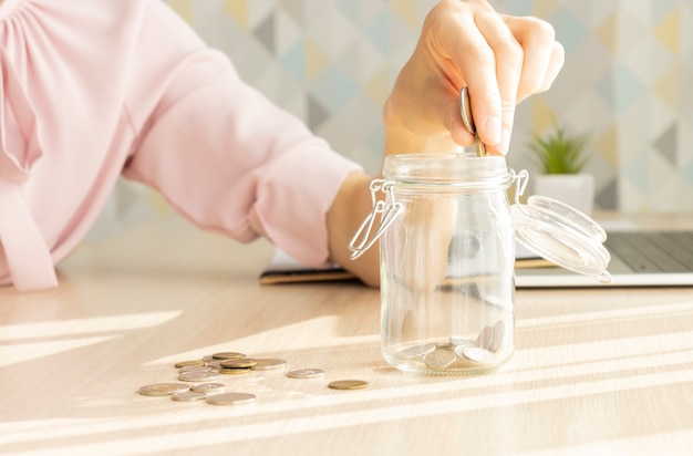 The girl counts and stacks coins in a glass jar