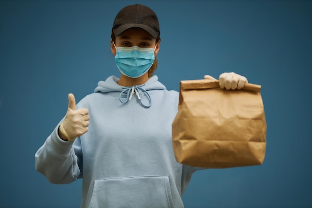 Girl courier in a medical mask and medical gloves on blue background