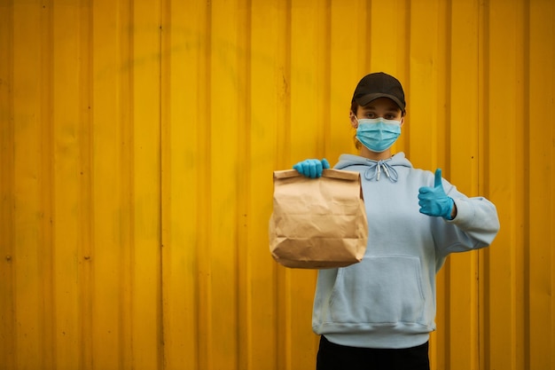 Corriere ragazza con maschera medica e guanti medici su sfondo giallo