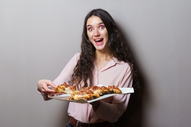 Girl courier with pinsa romana gourmet italian cuisine. Holding scrocchiarella traditional dish. Pinsa with meat, arugula, olives, cheese.