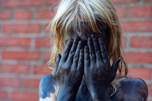 Photo girl covered in powder paint while hiding face against brick wall