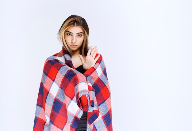 Photo girl covered with red blanket pointing at something.