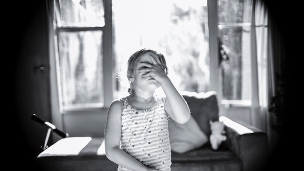 Photo girl covering face with hand while standing at home