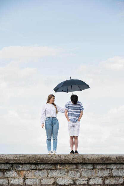 Girl covering sad boy with umbrella