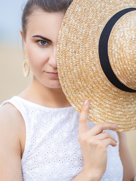 A girl covers half of her face with a straw hat