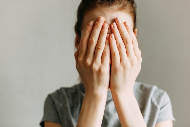 The girl covers her face with her hands and cries. Stop domestic violence against women.