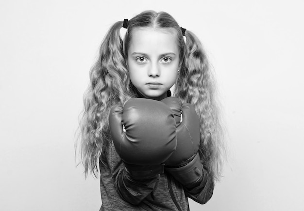 Girl cute child with red gloves posing on white background Cute kid with sport boxing gloves Boxing sport for female Sport upbringing Skill of successful leader Sport upbringing for leader