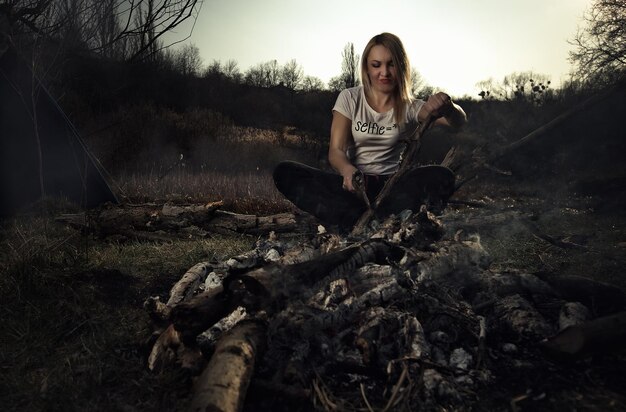 Foto una ragazza taglia la legna per il fuoco durante un picnic