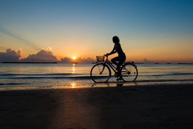 Girl cycling in the sea during sunrise