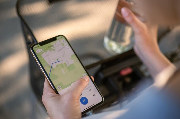 Girl cyclist looks at a map on her phone and plots a route for a trip for a GPS navigator