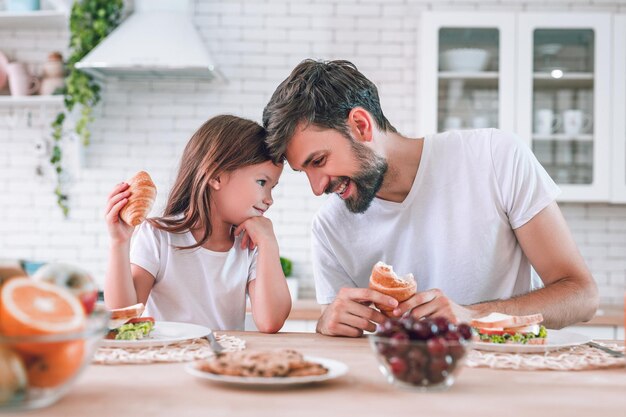 Ragazza e papà che fanno colazione insieme sulla cucina domestica