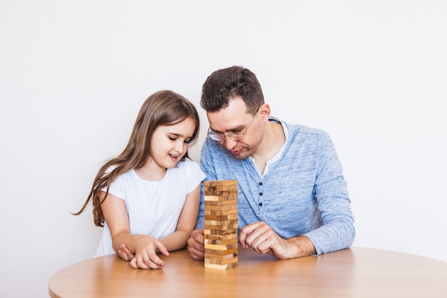 Foto ragazza e papà giocano a casa, costano una torre di blocchi, cubi, jenga, puzzle per lo sviluppo del cervello, intelligenza mentale