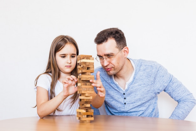 Ragazza e papà giocano a casa, costano una torre di blocchi, cubi, jenga, puzzle per lo sviluppo del cervello, intelligenza mentale