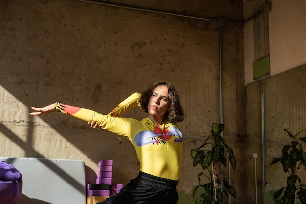 A girl dances a contemporary dance in a sunlit studio