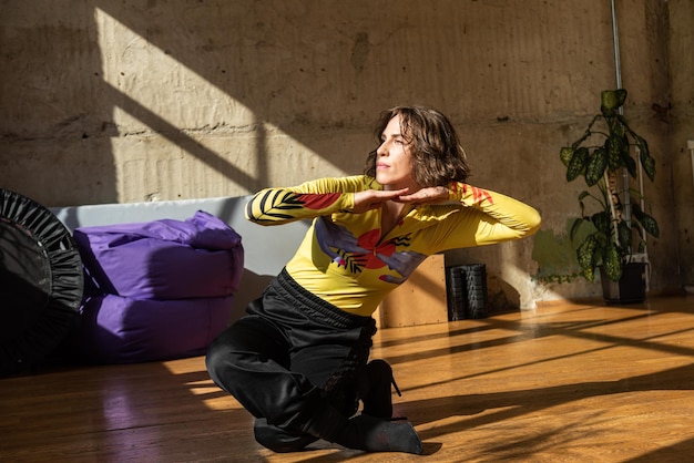 A girl dances a contemporary dance in a sunlit studio