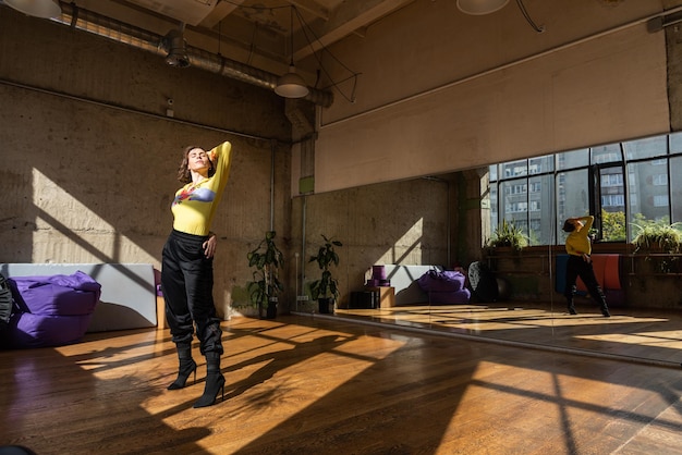 A girl dances a contemporary dance in a sunlit studio