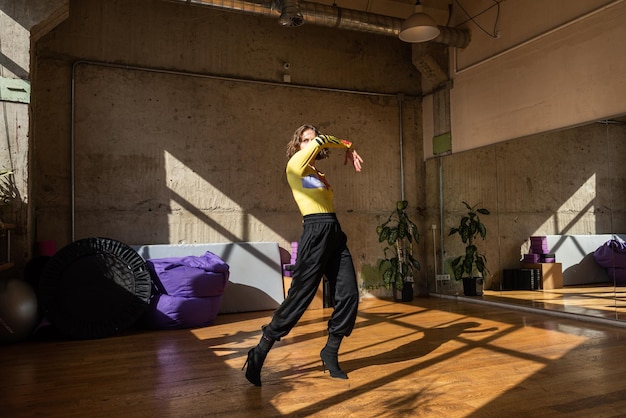 A girl dances a contemporary dance in a sunlit studio