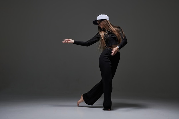 A girl in dark clothes dances and jumps on a dark background background modern dance