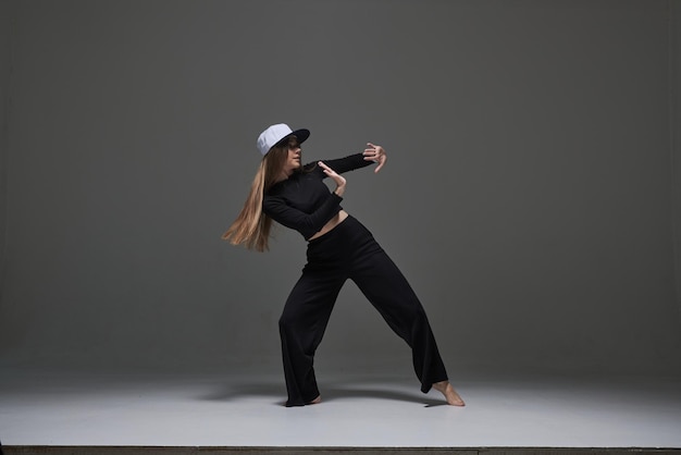 A girl in dark clothes dances and jumps on a dark background background modern dance