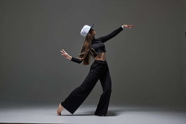 Девушка в темной одежде танцует и прыгает на темном фоне на фоне современного танца