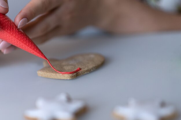 Photo a girl decorates christmas cookies with white icing sugar