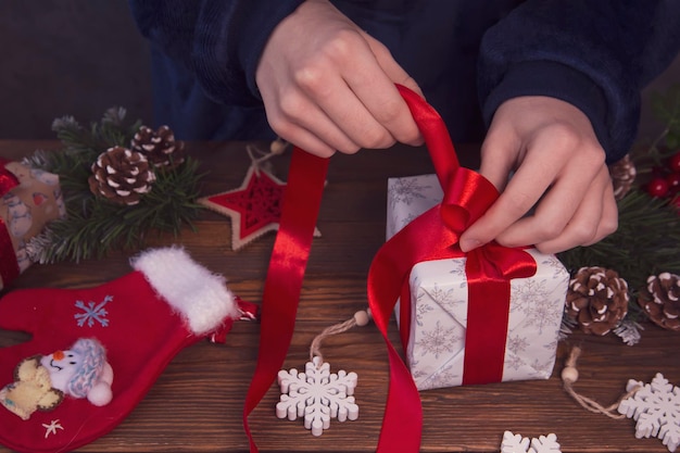 Girl decorates Christmas gifts Top view on wooden table background Celebrating Christmas and New Years