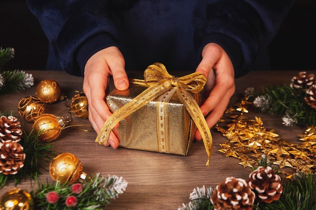 Girl decorates Christmas gifts Top view on wooden table background Celebrating Christmas and New Years